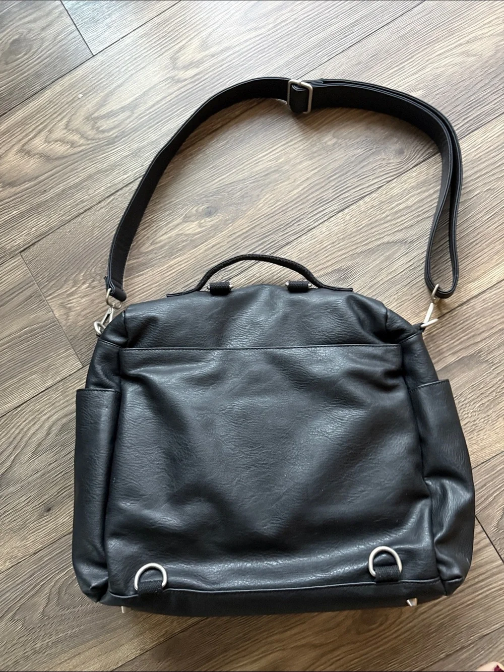 The Honest Company Black Vegan Leather Diaper Bag backpack model cross country